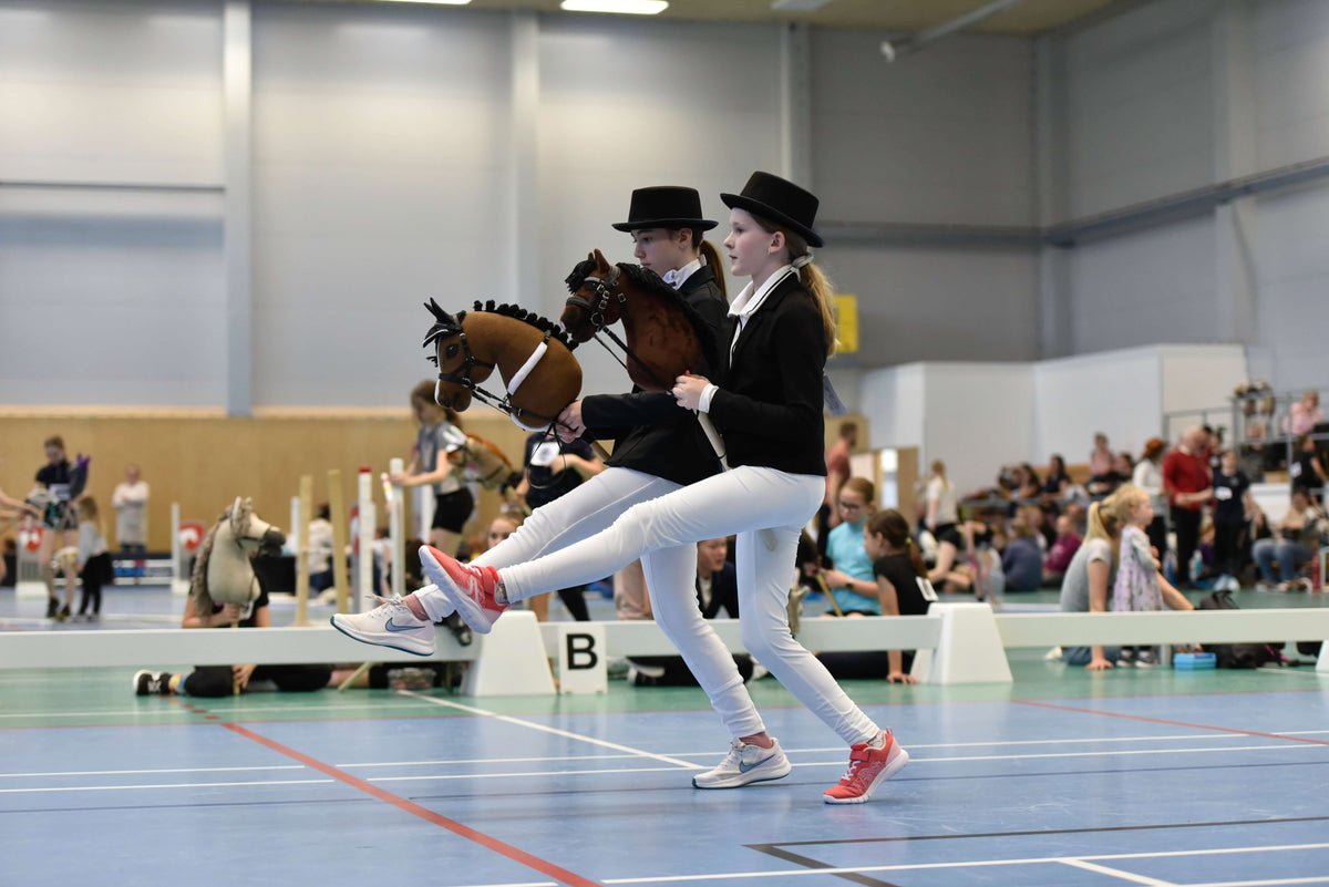 Dvě děti ve slavnostních oděvech podle pravidel soutěží v hale s Hobby Horses