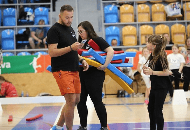 Denny připravuje barevné skokové překážky pro Hobby Horse s mladým účastníkem Hobby Horsing ve sportovní hale