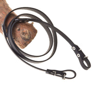 Otěže pogumované černé od Hobby Horse LarDen omotané kolem kusu dřeva a zobrazené na bílém pozadí, s hladkým černým povrchem a texturovanými detaily.