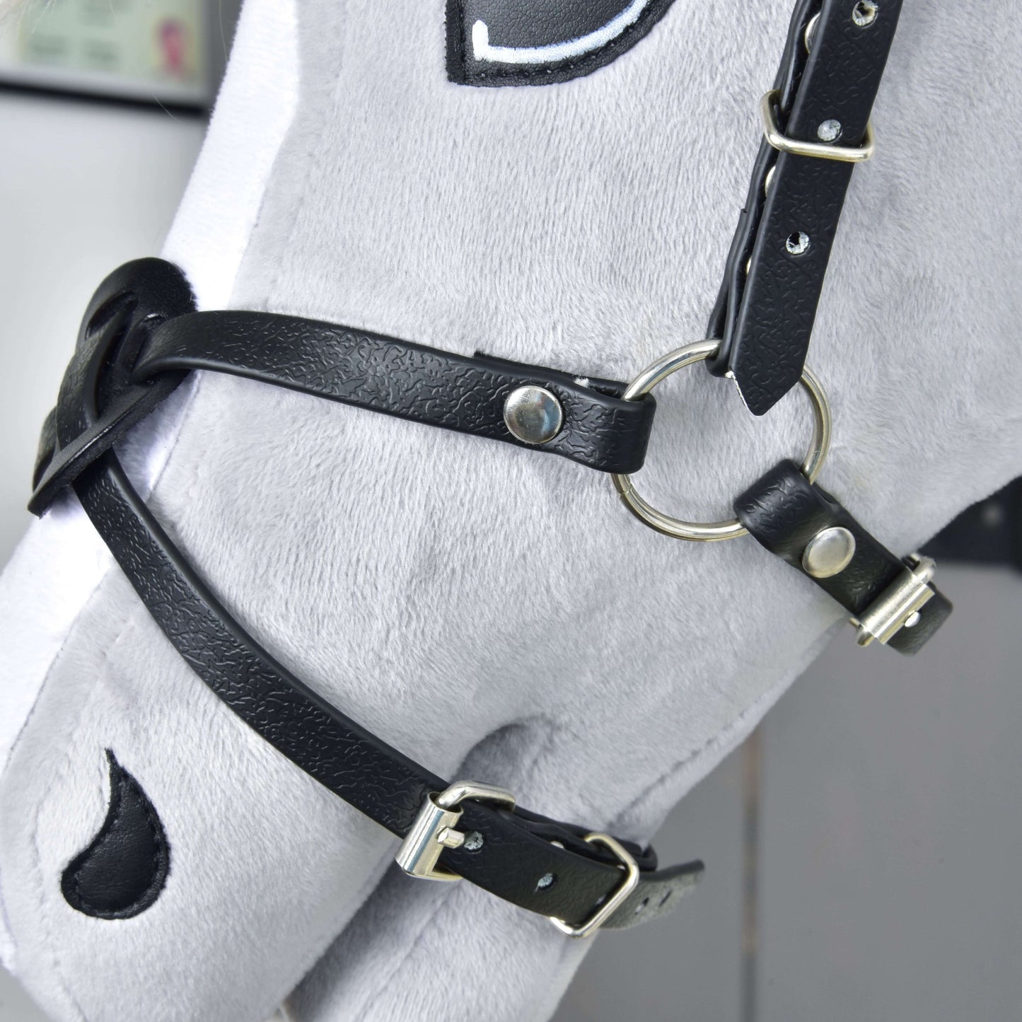 Mexický nánosník černý na šedé hlavě Hobby Horse LarDen, s černou koženkou, kovovými přezkami a kroužky. Plyš má vyšívané detaily včetně černého oka a nozdry.