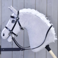 Detail šedého plyšového hobby horse s bílou hřívou na dřevěné tyči, s černou uzdečkou z koženky od Hobby Horse LarDen, na pozadí světlých dřevěných panelů.
