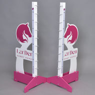 Dva stojany Překážka LarDen kolmák 110 cm od Hobby Horse LarDen v růžové a bílé barvě s motivy koňských hlav, značkami nastavitelné výšky a kovovými držáky na tyče stojí na šedém pozadí. Na základně je vytištěno „LarDen HOBBY HORSE“.