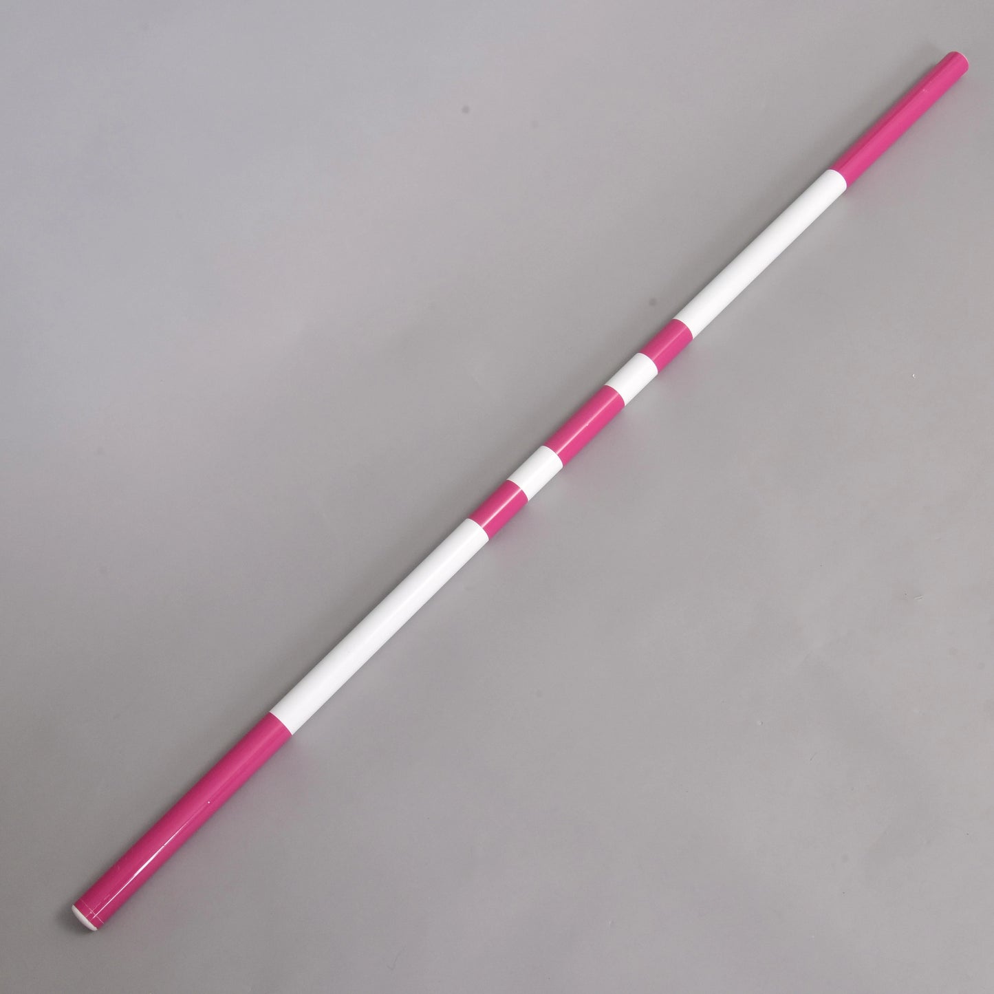 Bariérka růžová od Hobby Horse LarDen se střídajícími se růžovými a bílými segmenty, zobrazená diagonálně na jednobarevném šedém povrchu.