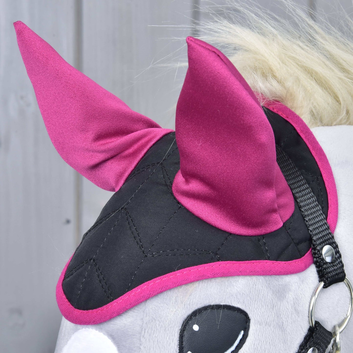 Detail čabraky Thermo Sky od Hobby Horse LarDen v černé a magentové barvě se dvěma špičatými magentovými ušima a prošívaným vzorem, poskytující ochranu proti hmyzu, na světlém dřevěném pozadí.