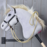Hobby Horse LarDen Westernové otěže Dakota, šedý Hobby Horse s blond hřívou, černou uzdečkou a žlutým lanem s karabinami, visí na dřevěné stěně v černém držáku – ideální pro tréninky.