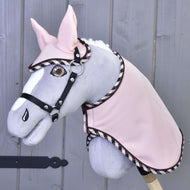Set Abby od Hobby Horse LarDen je šedobílý plyšový Hobby Horse s plyšovou hřívou, vyšívaným okem a růžovou uzdečkou a dekou, zobrazený před světlou dřevěnou stěnou.