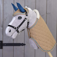 Set Almond Star od Hobby Horse LarDen s plyšovým Hobby Horse, béžovou prošívanou dekou, modrou čabrakou, bílou hřívou a černou uzdečkou na dřevěné tyči, zobrazený před šedou dřevěnou stěnou.