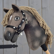 Hobby Horse Avalon s černou ohlávkou, velikost XS, od Hobby Horse LarDen, detail ručně vyrobeného Hobby Horse s hnědou srstí, přízovou hřívou a malou bílou skvrnou na čele. Inspirován sportovním koněm plemene English Warmblood, před šedými dřevěnými panely.