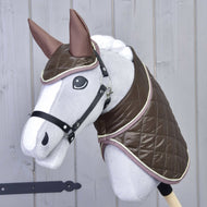 Set Thermo Chocolate od Hobby Horse LarDen na šedém Hobby Horse s velkýma očima, lesklou hnědou prošívanou dekou a ladící čabrakou, nasazeném na tyči před světlou dřevěnou stěnou.