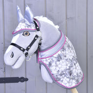 Set Grey Flower od Hobby Horse LarDen na šedém plyšovém Hobby Horse s černou uzdečkou, stříbrno-růžovým vybavením, květinovým vzorem a ladící dečkou, na pozadí ze světle šedého dřeva.