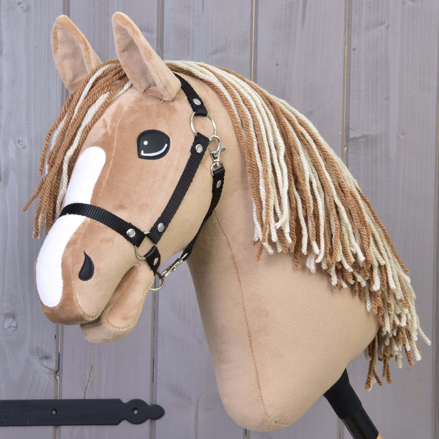 Hobby Horse Bren s černou ohlávkou od Hobby Horse LarDen, se světle hnědým tělem, bílými znaky na hlavě a dlouhou přízovou hřívou, na dřevěném pozadí.