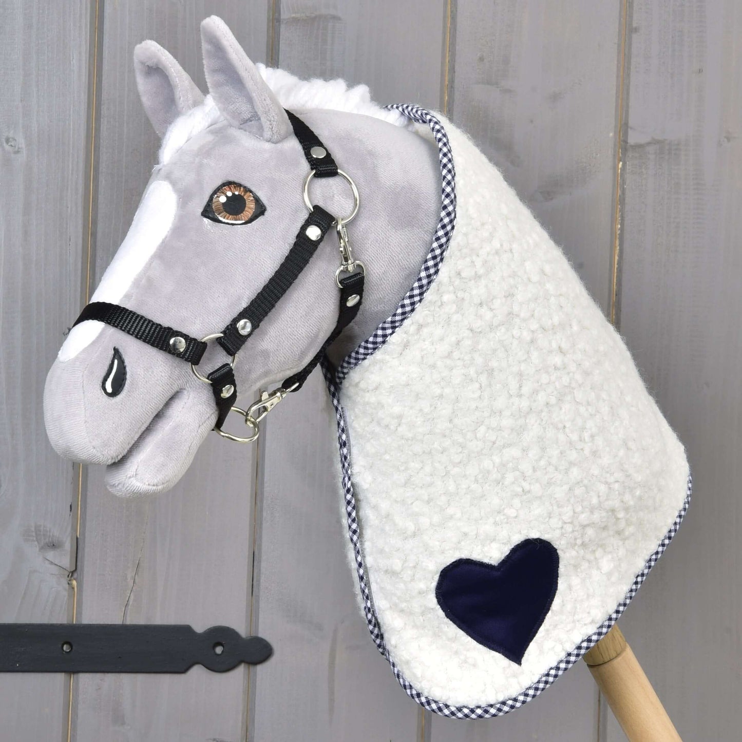 Deka Cube Blue od Hobby Horse LarDen na plyšovém Hobby Horse se šedým obličejem, černou uzdečkou a dekou s modrým akcentem, nasazeném na dřevěné tyči, na dřevěném pozadí.