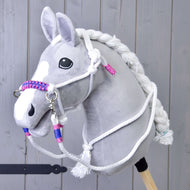 Provazový set Bílý (vel. M) od Hobby Horse LarDen na šedém plyšovém Hobby Horse s bílou hřívou, otěžemi a pletenou ohlávkou s růžovými a modrými akcenty, na dřevěném pozadí.