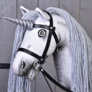 Hobby Horse jednorožec Silver s uzdou a ohlávkou od Hobby Horse LarDen s kouzelnou hlavou jednorožce, stříbrným rohem, dlouhou šedou hřívou z příze a černou koženou uzdou na dřevěném pozadí.