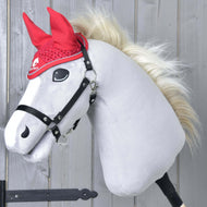 Plyšový Hobby Horse od Hobby Horse LarDen s bílým obličejem, černou uzdečkou a blonďatou hřívou předvádí čabraku Čabraka háčkovaná Red sport před světlou dřevěnou stěnou.