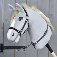 Detailní záběr na Martingale tmavě šedá od Hobby Horse LarDen na plyšovém šedém Hobby Horse s bílou hřívou, černou uzdečkou a martingalem z koženky, nasazeném na dřevěné tyči před šedou dřevěnou stěnou.