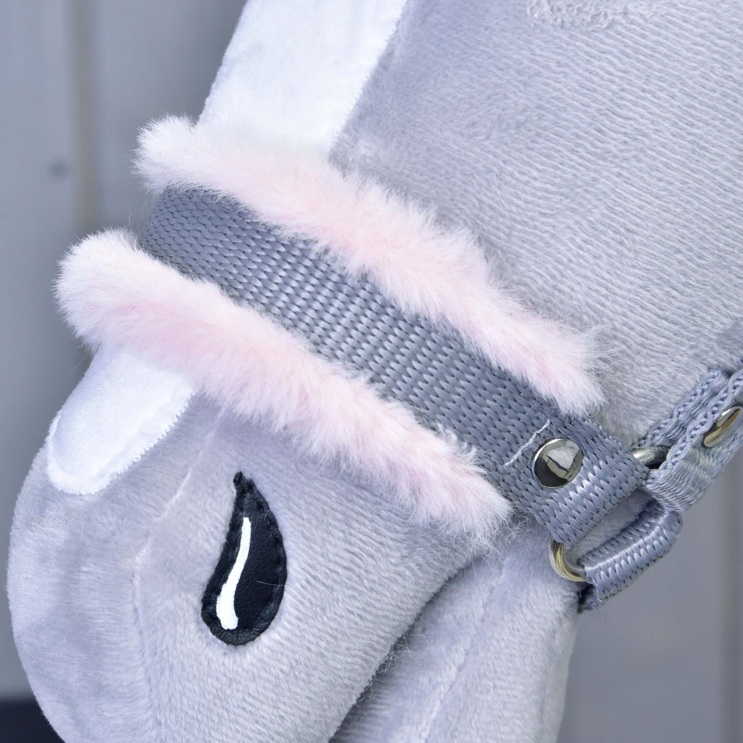 Detailní záběr na Ohlávka šedá s růžovým beránkem od Hobby Horse LarDen s plyšovou šedou látkou, bílou skvrnou, růžovým lemem z umělé kožešiny, vyšívaným černým detailem ve tvaru kapky a kovovými cvočky – ideální pro vaše plyšové zvířátko nebo Hobby Horse.