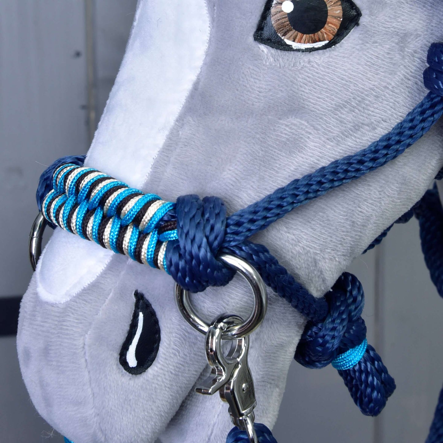 Detailní záběr na plyšového Hobby Horse LarDen s Provazový set Navy, modro-bíle pletenou ohlávkou a vodítkem. Detailní prošití tvaruje oko a nos, zatímco otěže dodávají autentický vzhled.