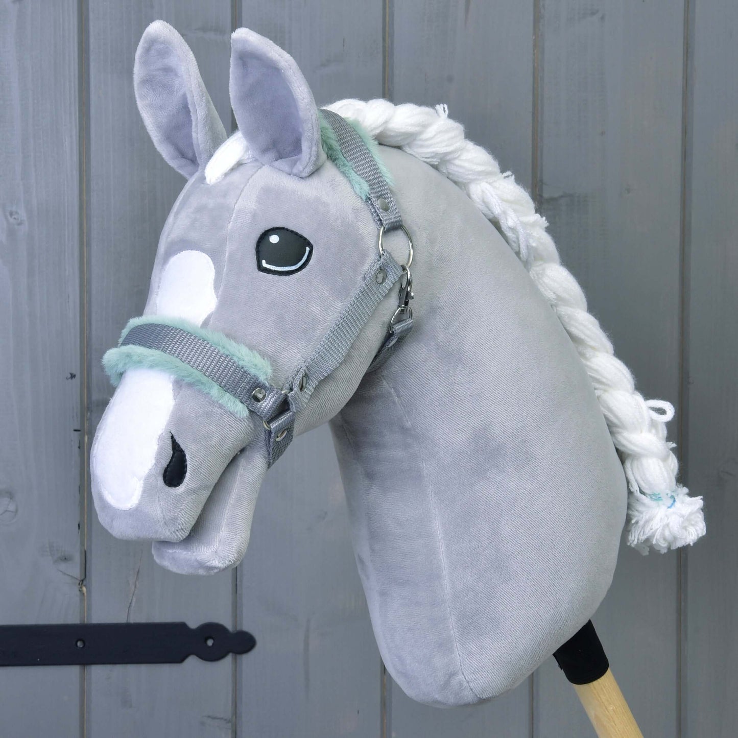 Hobby Horse LarDen Ohlávka šedá s mint beránkem – plyšový šedý doplněk pro Hobby Horse s bílou hřívou a znaky na hlavě – na šedém dřevěném pozadí.