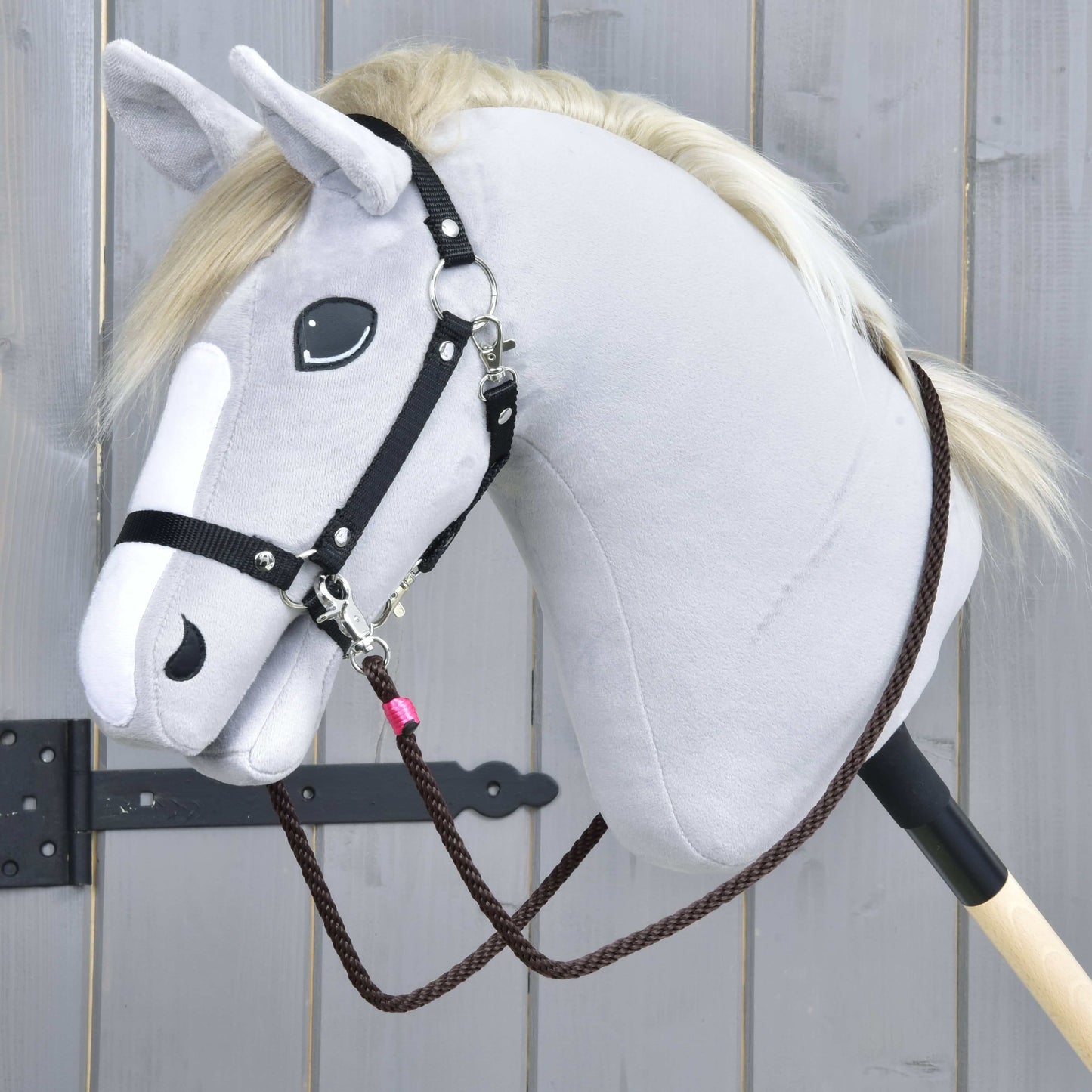 Detail Provazového setu Noir Cocoa od Hobby Horse LarDen – šedý plyšový Hobby Horse s černou uzdečkou, ohlávkou a hnědými otěžemi na dřevěné tyči na světle dřevěném pozadí.