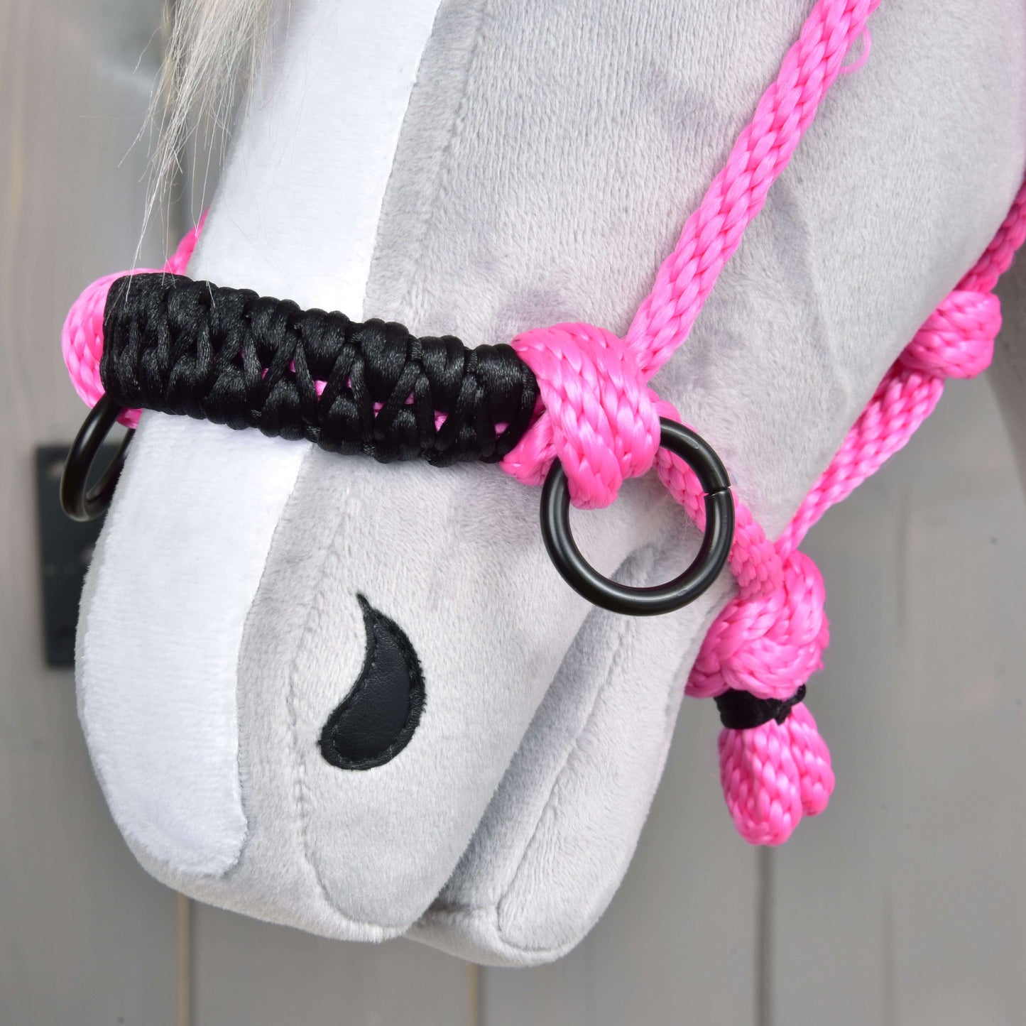 Detail obličeje šedého plyšového koně s Parelka Pink od Hobby Horse LarDen s výrazným růžovým lanem, černými a růžovými uzly, kovovými kroužky a černě prošitou nozdrou.