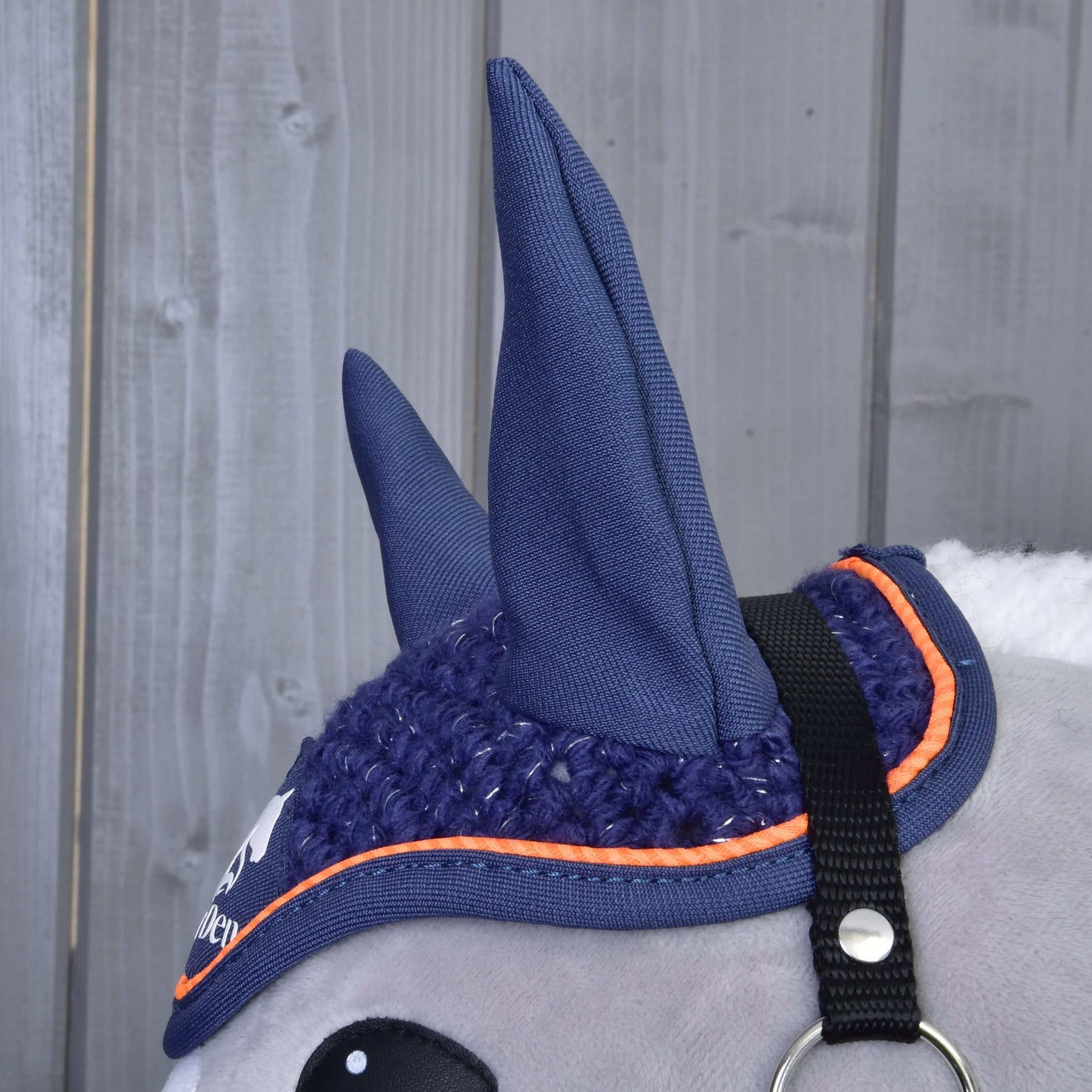 Detail čabraky Čabraka háčkovaná Blue sport od Hobby Horse LarDen na hlavě hračkového koně. Tato modrá čabraka s oranžovým lemováním a černým páskem má dvě vztyčené uši a chrání Hobby Horse před hmyzem.