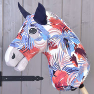 Hobby Horse ochranný oblek Blue Jungle (Lycra) od Hobby Horse LarDen má výrazný abstraktní vzor v červené, bílé, fialové a modré barvě s černýma očima a tmavýma ušima. Obsahuje pratelný potah a je zobrazený na dřevěné tyči u šedé stěny.