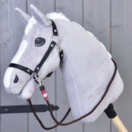 Hobby Horse LarDen Otěže York, šedý plyšový Hobby Horse s bílou hřívou a čenichem, s černými ručně vyráběnými polypropylenovými provazovými otěžemi, nasazený na dřevěné tyči na pozadí dřevěného obložení.