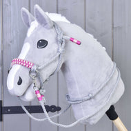 Provazový set Rosie od Hobby Horse LarDen, šedý plyšový Hobby Horse s bílou lysinou, černýma očima a růžovo-šedou uzdečkou s otěžemi na dřevěné tyči, je zobrazený před světle šedou dřevěnou stěnou.