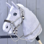 Provazový set Splendid od Hobby Horse LarDen na šedém plyšovém Hobby Horse s bílou hřívou, černýma očima a provazovou uzdečkou s otěžemi, před šedou dřevěnou stěnou.