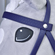 Detail obličeje plyšového koně s vyšitým černo-bílým okem, s Kompletní uzdečka s nánosníkem Dark Purple od Hobby Horse LarDen; uzdečka má stříbrný knoflíkový detail a srst koně je světle šedá.