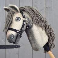 Hobby Horse Dusty s černou ohlávkou ve velikosti XS od Hobby Horse LarDen s plyšovým hannoverským provedením a šedou přízovou hřívou je zobrazený na pozadí šedého dřeva.
