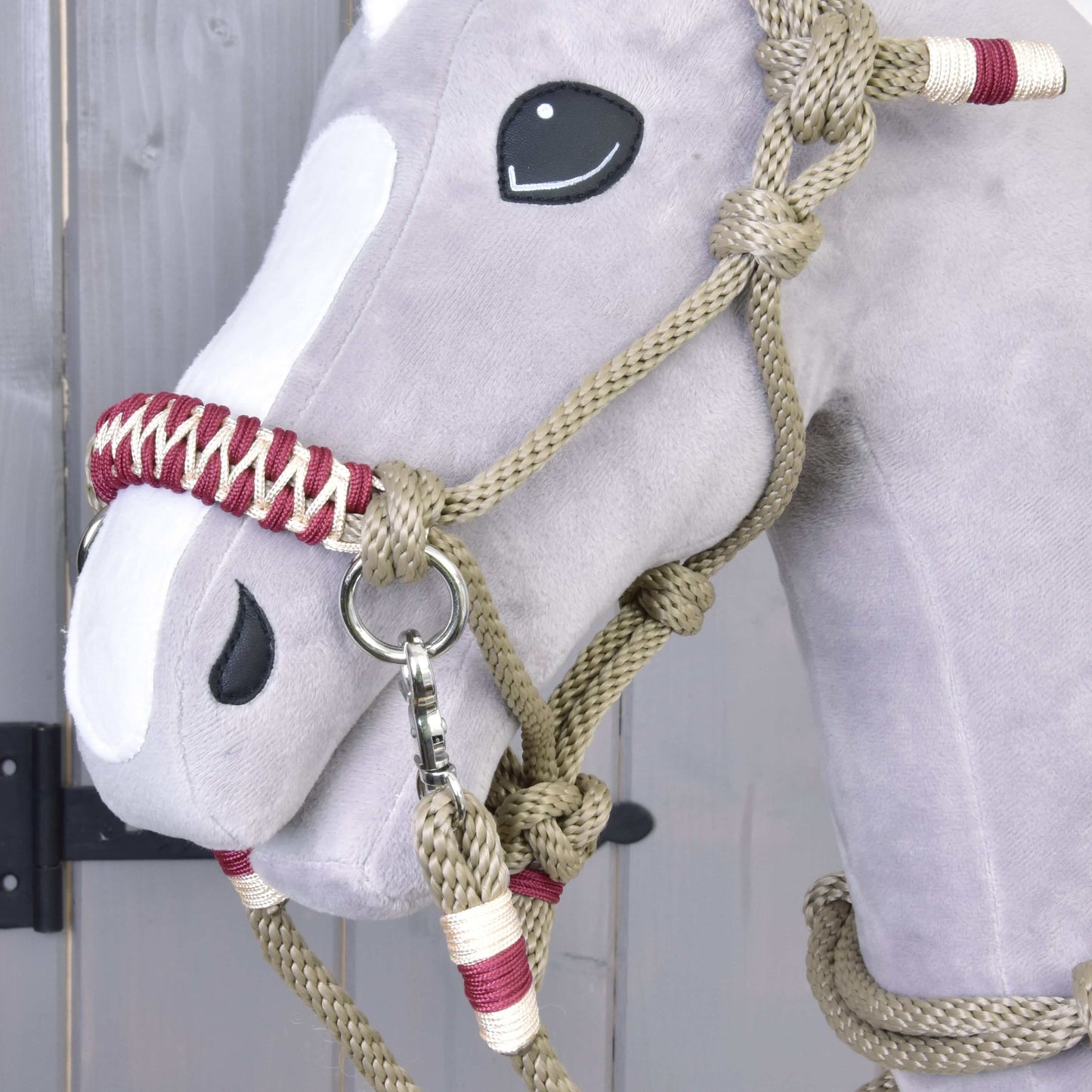 Detail hlavy Hobby Horse LarDen s provazovým setem Eleganza – měkký šedý Hobby Horse s černýma knoflíkovýma očima, bílými plstěnými částmi a béžovo-červenou ohlávkou na dřevěném pozadí.