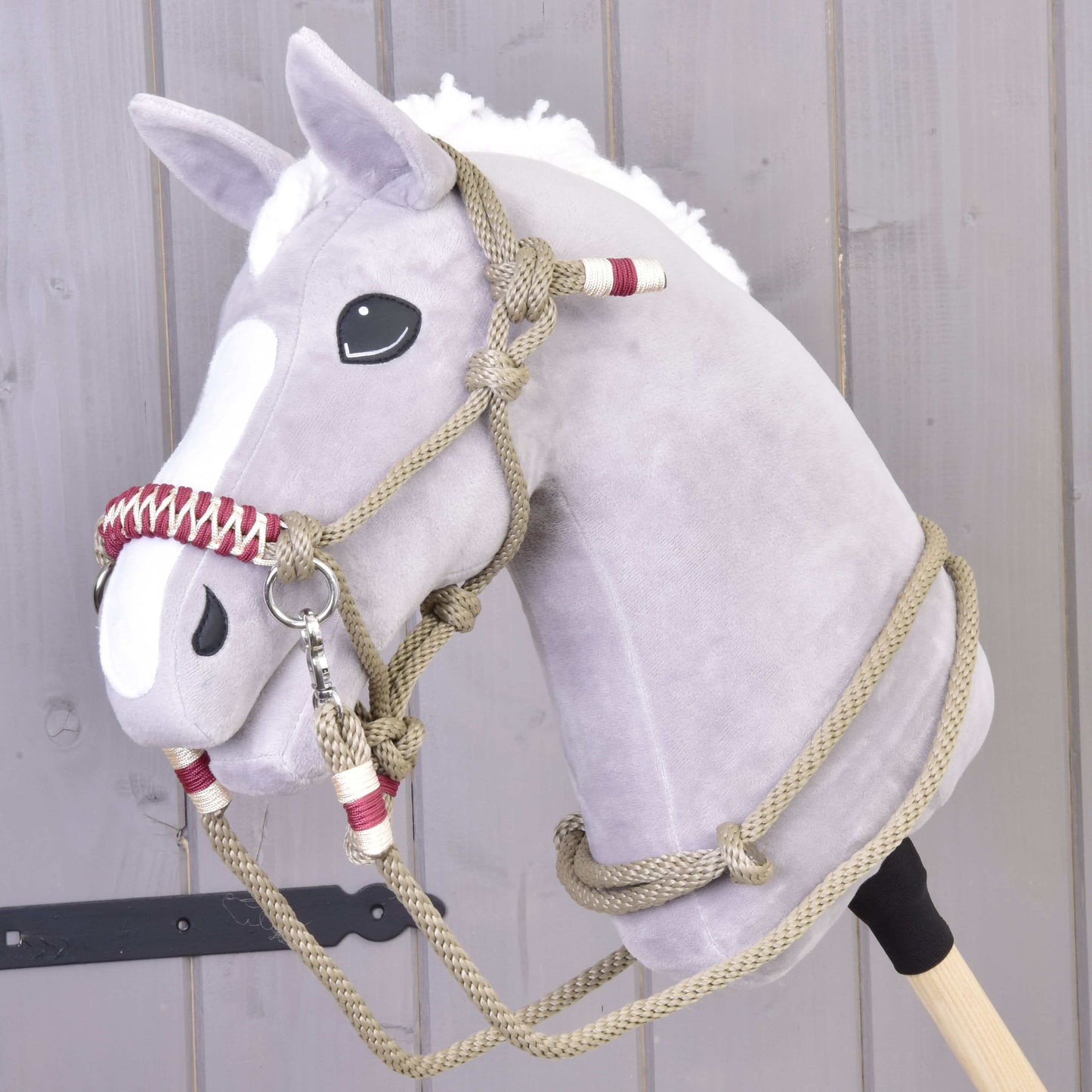 Šedý plyšový Hobby Horse s bílou hřívou a lysinou, který má na sobě provazový set Eleganza od Hobby Horse LarDen, stojí před světlou dřevěnou stěnou.