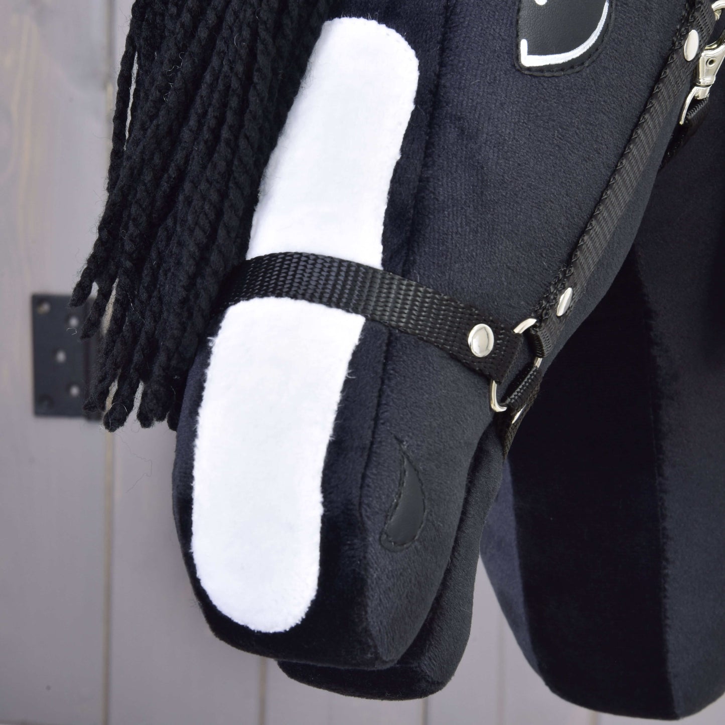 Detail Hobby Horse Freya s černou ohlávkou od Hobby Horse LarDen s přízovou hřívou, látkovou uzdečkou a bílou skvrnou na obličeji inspirovanou plemenem Irish Cob, na neutrálním pozadí.