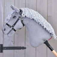 Hobby Horse Grace s černou ohlávkou od Hobby Horse LarDen, šedý holandský teplokrevník s hřívou z příze, na dřevěné tyči, zobrazený před stěnou z dřevěných panelů.