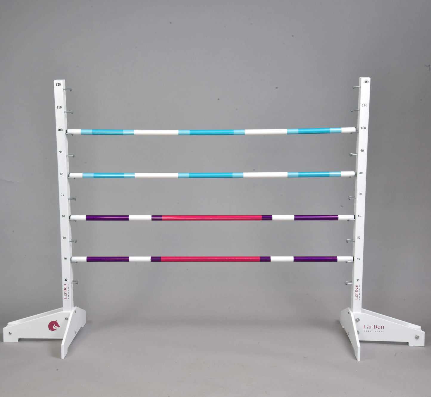 Set překážky kolmák 120 cm + 2 ks bariérky od Hobby Horse LarDen s pěti pruhovanými tyčemi v modré, bílé, fialové a červené barvě, dvěma nastavitelnými bílými stojany, vhodný pro Hobby Horsing uvnitř i venku. Jednolité šedé pozadí.