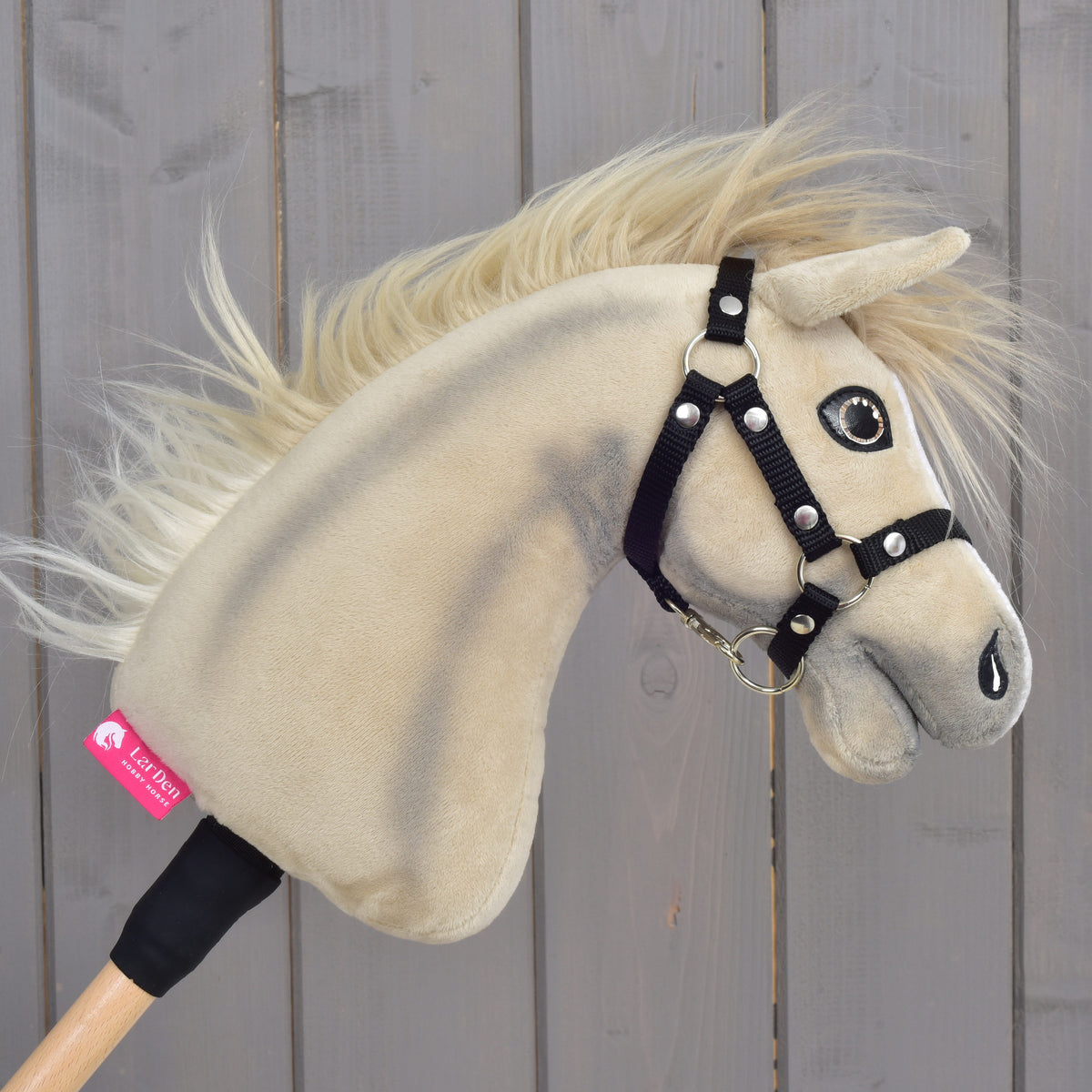 Detail Hobby Horse Ivory Dream s černou ohlávkou – velikost XS od Hobby Horse LarDen, s béžovým plyšovým provedením, černou ohlávkou a štítkem na krku, na pozadí dřevěných prken.