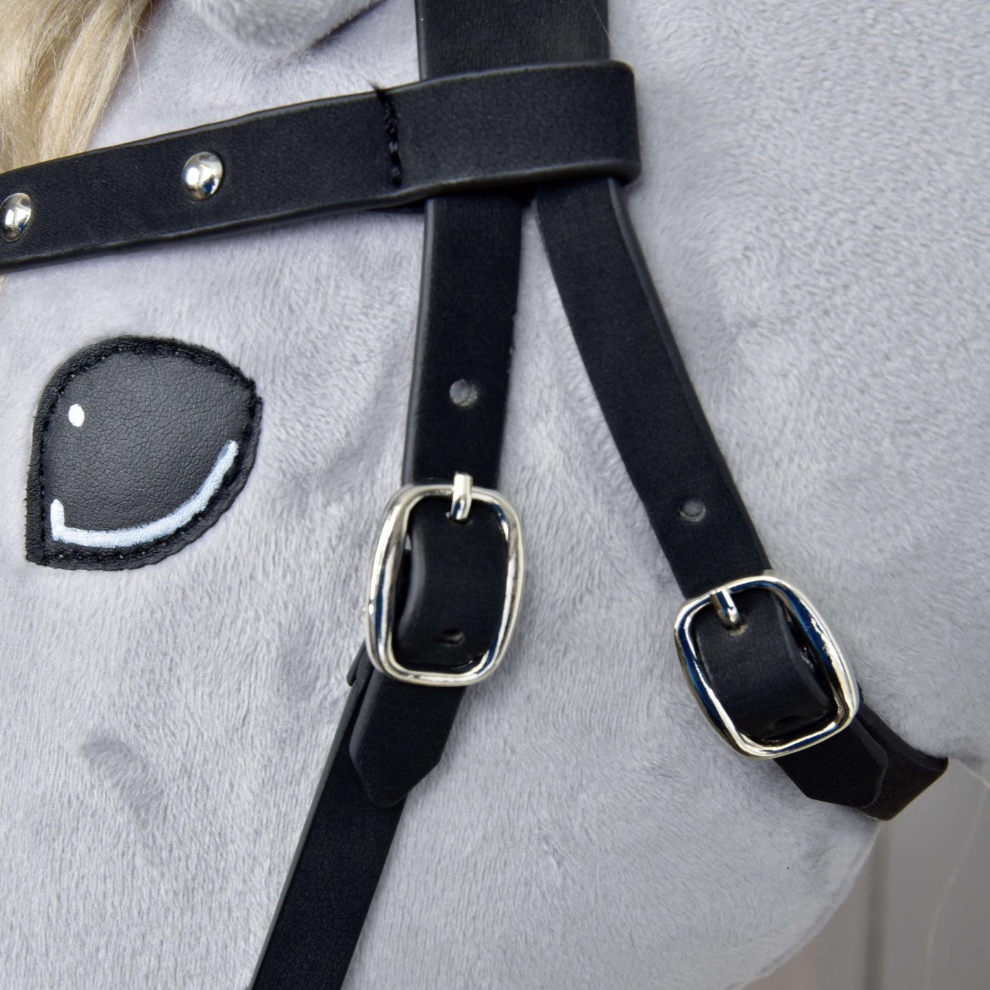 Detail Kompletní uzdečky bezudidlové zdobené od Hobby Horse LarDen – světlá měkká látka, vyšívané kreslené oko a černé řemínky z umělé kůže s lesklými stříbrnými přezkami a odnímatelnými otěžemi.