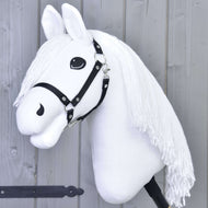 Hobby Horse Lady s černou ohlávkou od Hobby Horse LarDen s bílou hlavou, černou ohlávkou a dlouhou přízovou hřívou na tyči, naaranžovaná jako připravená na drezuru před světle šedou dřevěnou stěnou.