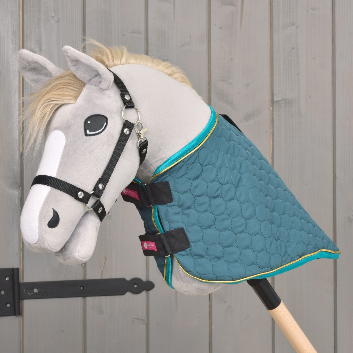 Pohled z boku na zelenou prošívanou deku pro Hobby Horse s tyrkysovým lemováním a odnímatelným nákrčníkem