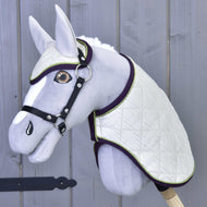 Set Leonardo od Hobby Horse LarDen se šedým plyšovým Hobby Horse s bílou prošívanou dekou, ladící čabrakou, černou uzdečkou a otěžemi na dřevěné tyči, zobrazený na pozadí šedé dřevěné stěny.