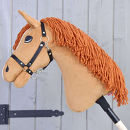Hobby Horse Little Angel s černou ohlávkou od Hobby Horse LarDen má bílé akcenty a oranžovou hřívu z příze, je upevněn na tyči a zobrazen na světle šedém dřevěném pozadí.