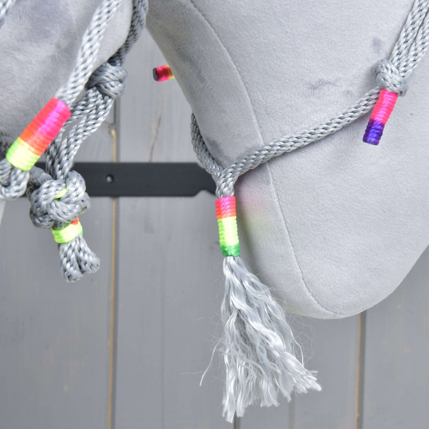 Provazový set Manhattan od Hobby Horse LarDen v detailu, se šedým provazem s vícebarevným omotáním a střapcem, přehozeným přes světle šedý povrch, s dřevěnými prkny v pozadí.