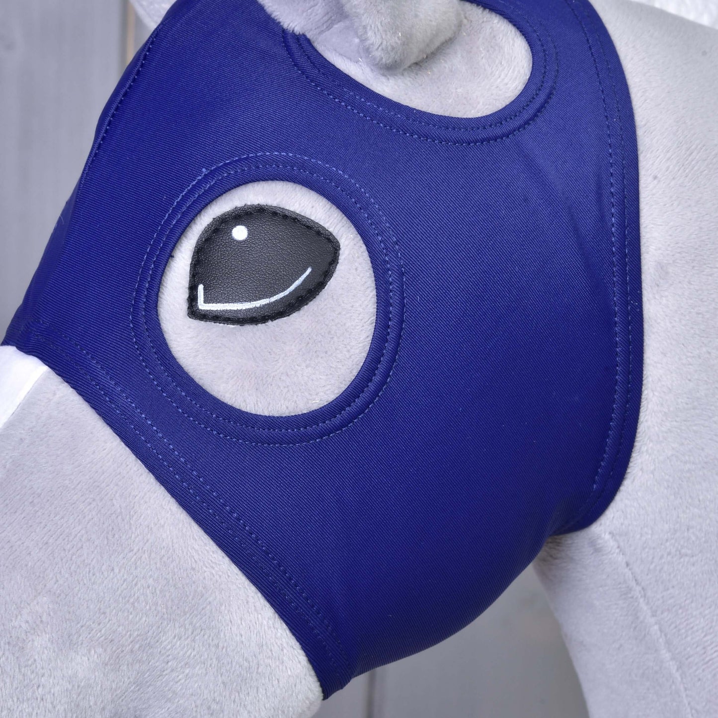 Detail hlavy koňské figuríny s maskou bez uší Hobby Horse LarDen, přiléhavou královsky modrou lycrovou maskou, která zakrývá obličej a má otvory na oči v kresleném stylu pro hravý vzhled.
