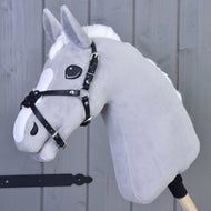 Mexický nánosník černý podšitý od Hobby Horse LarDen na šedém plyšovém Hobby Horse s bílou hřívou, černou uzdečkou a nánosníkem z koženky, na dřevěné tyči před šedým dřevěným obloženým pozadím.