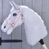 Hobby Horse LarDen Ohlávka s beránkem z koženky Mullbery na světle šedém plyšovém Hobby Horse s bílou hřívou, růžovou uzdečkou z koženky a vyšívanými detaily, nasazeném na dřevěné tyči před šedou dřevěnou stěnou.