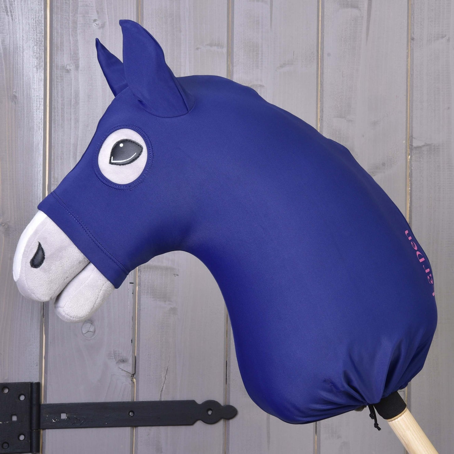 Hobby Horse ochranný oblek LarDen od Hobby Horse LarDen s modrou lycrovou hlavou, bílýma ušima a čumákem, černým kresleným okem a dřevěnou tyčí stojí před šedou dřevěnou stěnou.
