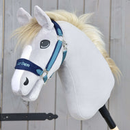 Hobby Horse LarDen s ohlávkou s beránkem LarDen Blue, se světle šedou plyšovou hlavou, bílou hřívou a modrou kožešinovou ohlávkou, upevněný na tyči na dřevěném pozadí.