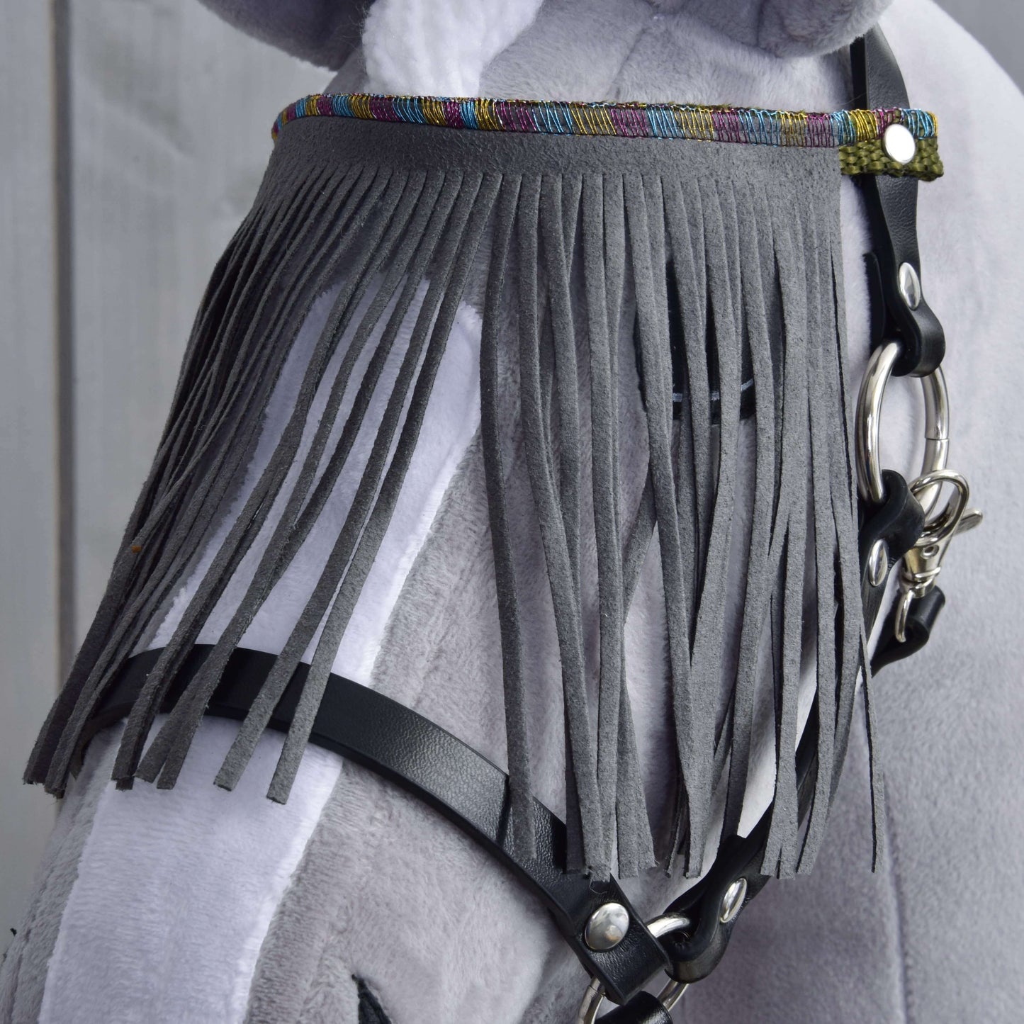 Detail světle šedobílého koně s Ohlávkou černou se šedými třásněmi od Hobby Horse LarDen, s dlouhými svislými třásněmi přes čelo a barevným lemem nahoře.